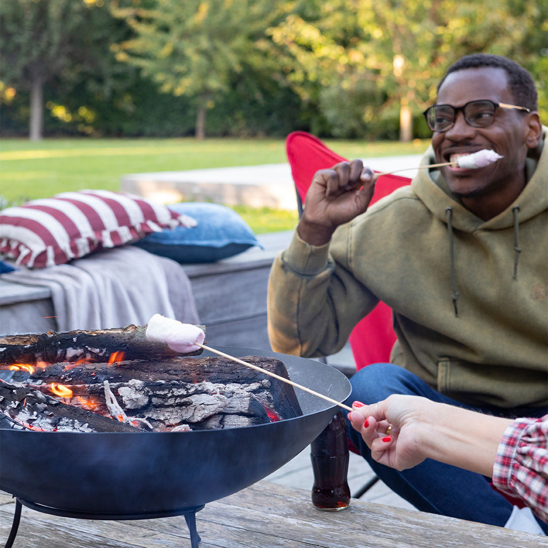People roasting marshmallows over a fire pit in an outdoor setting