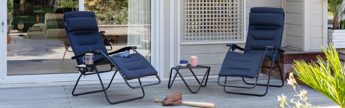 Two padded zero-gravity chairs on a porch