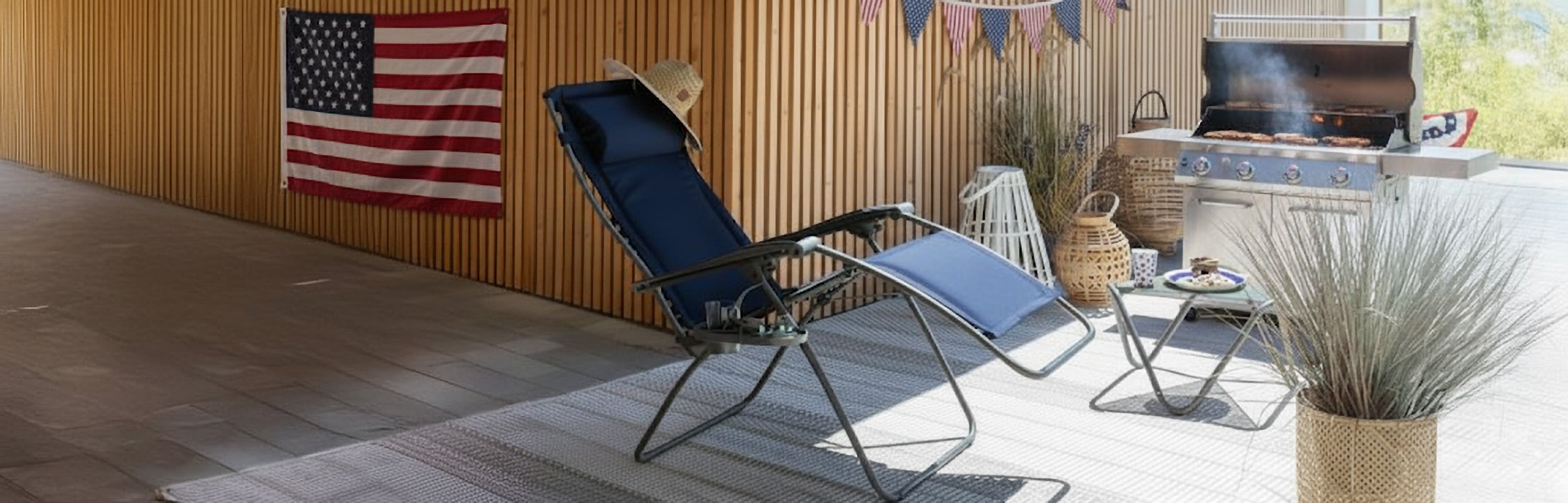 Outdoor zero-gravity chair, grill, and US flags for labor day