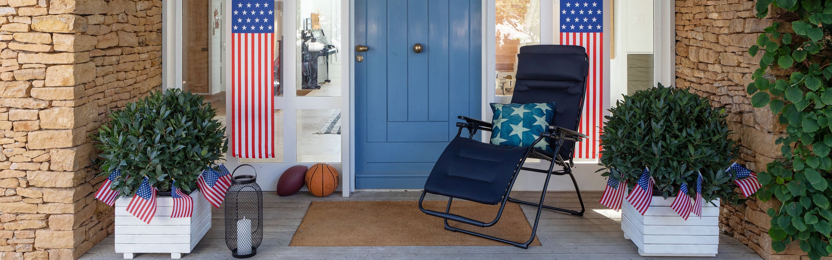 Front porch with reclining chair and blue door, American flags