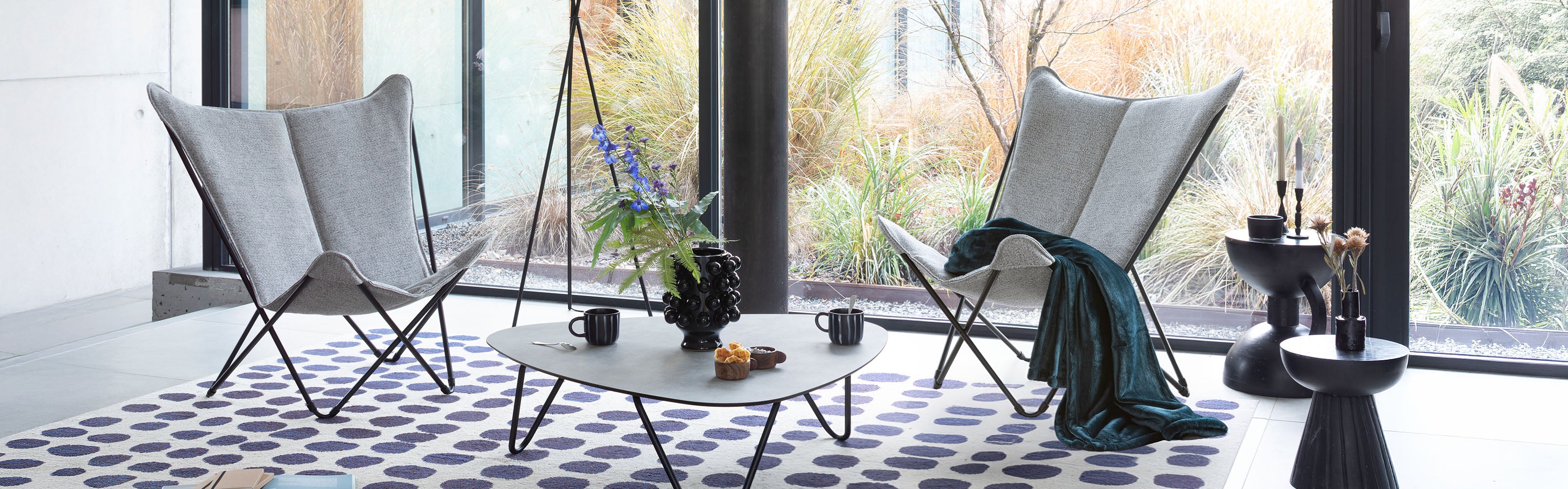 Two butterfly chairs  with a blanket and a table in a stylish living room.